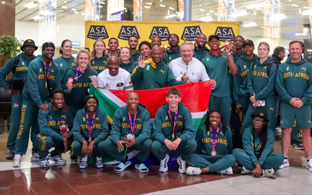 The combined SA National Relay team’s arrival at OR Tambo International Airport smile to record the moment with ASA President, James Moloi; SASCOC President, Barry Hendricks; and and Teboho Thebehae, Acting Deputy Director-General at the Department of Sport, Arts and Culture. All Photos: Cecilia van Bers