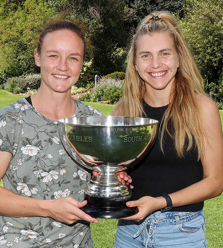 2026 champions (from left) Alexa Pienaar and Hayley Ward raise their trophy after retaining their SA women’s doubles squash title.